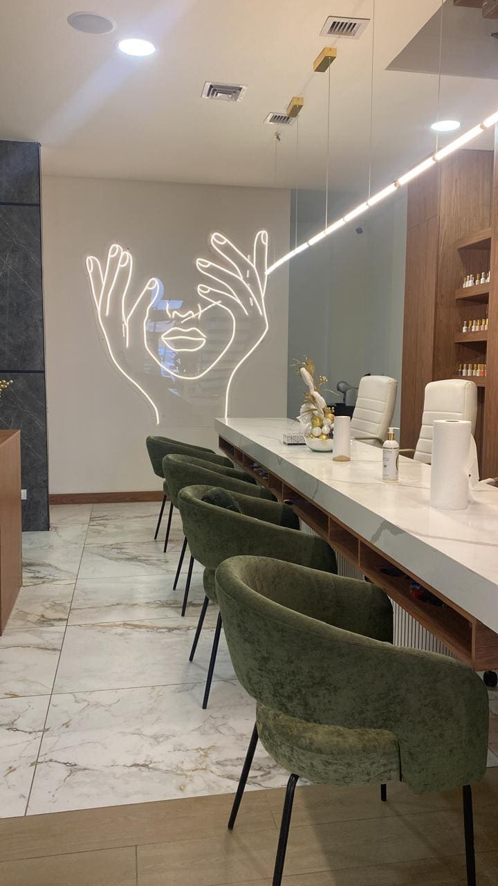 Nail bar con neón y sillones verdes